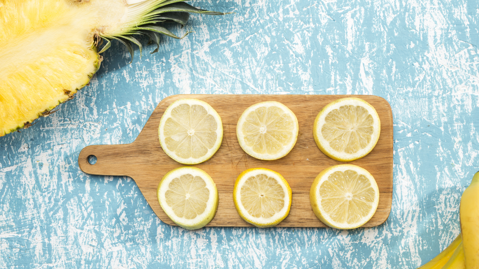Деревянная доска с лимоном на столе с ананасом