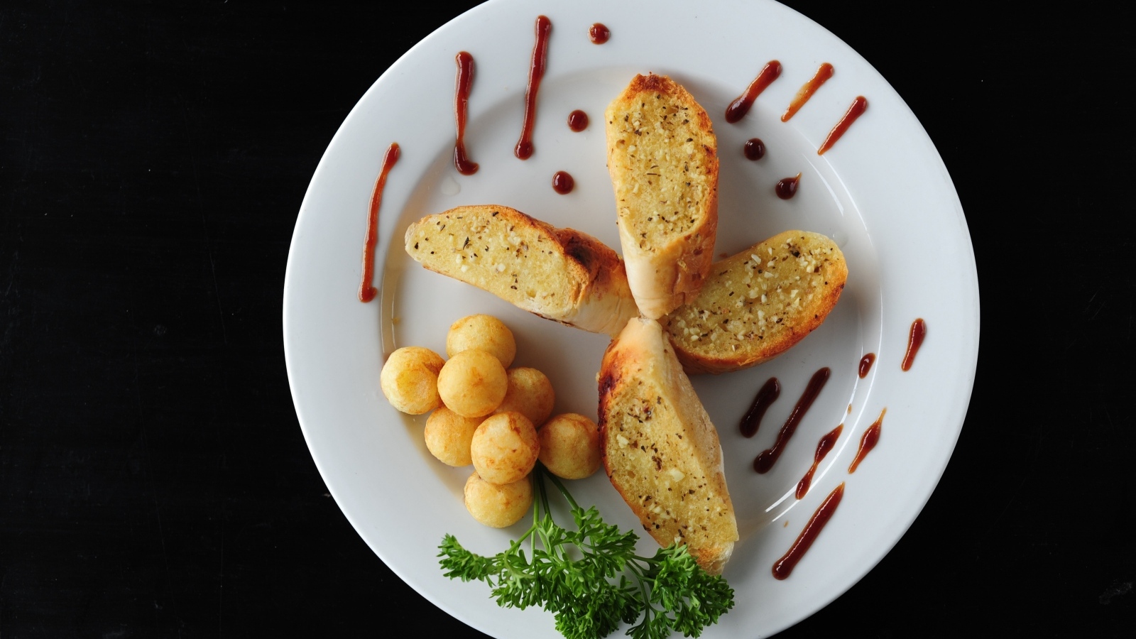 Чесночный хлеб на тарелке с картофельными шариками