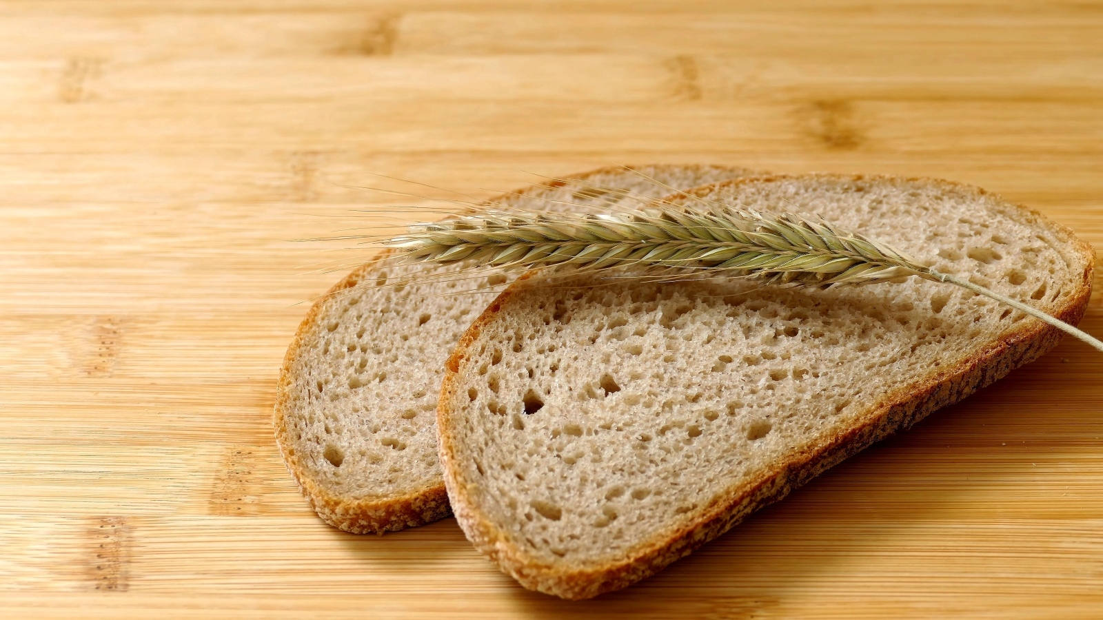 Два куска хлеба с колоском на деревянном столе
