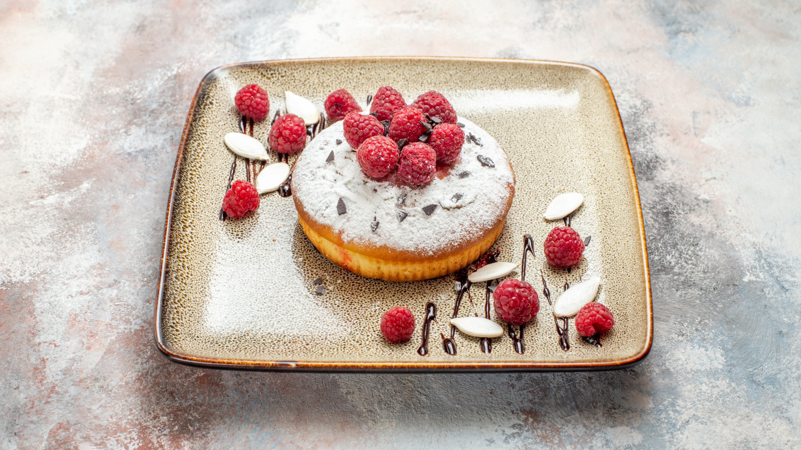 Пирожное с сахарной пудрой и малиной на тарелке