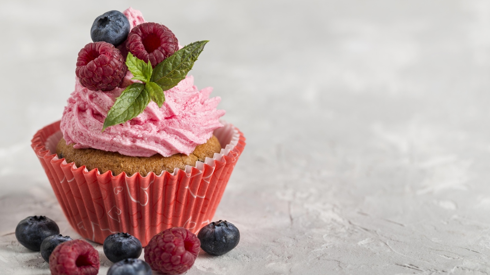 Маффин с розовым кремом и ягодами на столе