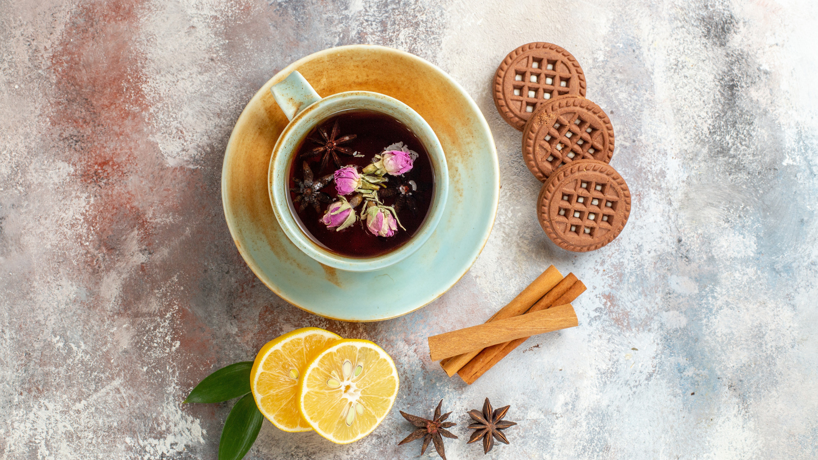 Чашка ароматного чая на столе с лимоном, печеньем и пряностями