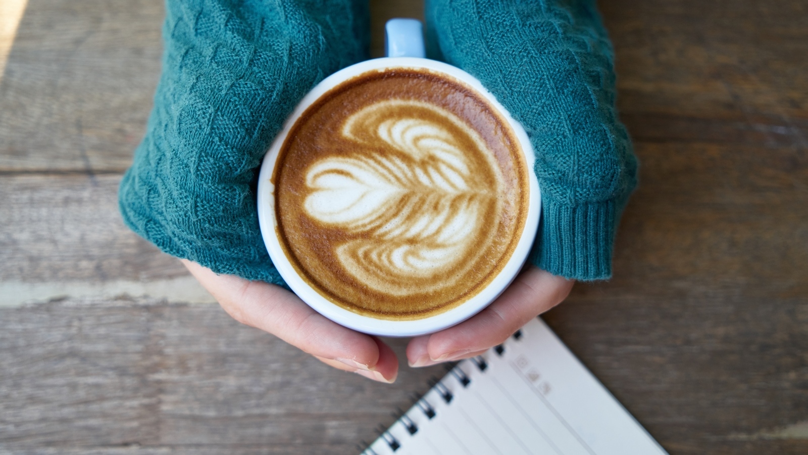 Горячая чашка кофе на столе в руках девушки