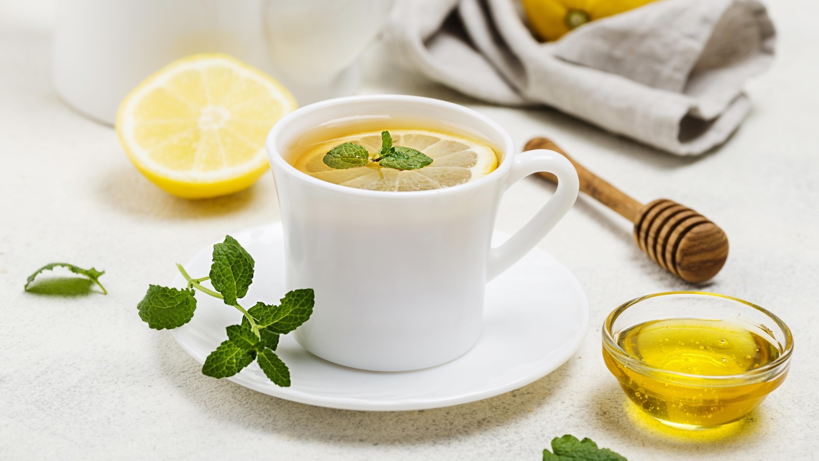 Белая кружка с чаем на столе с медом и лимоном