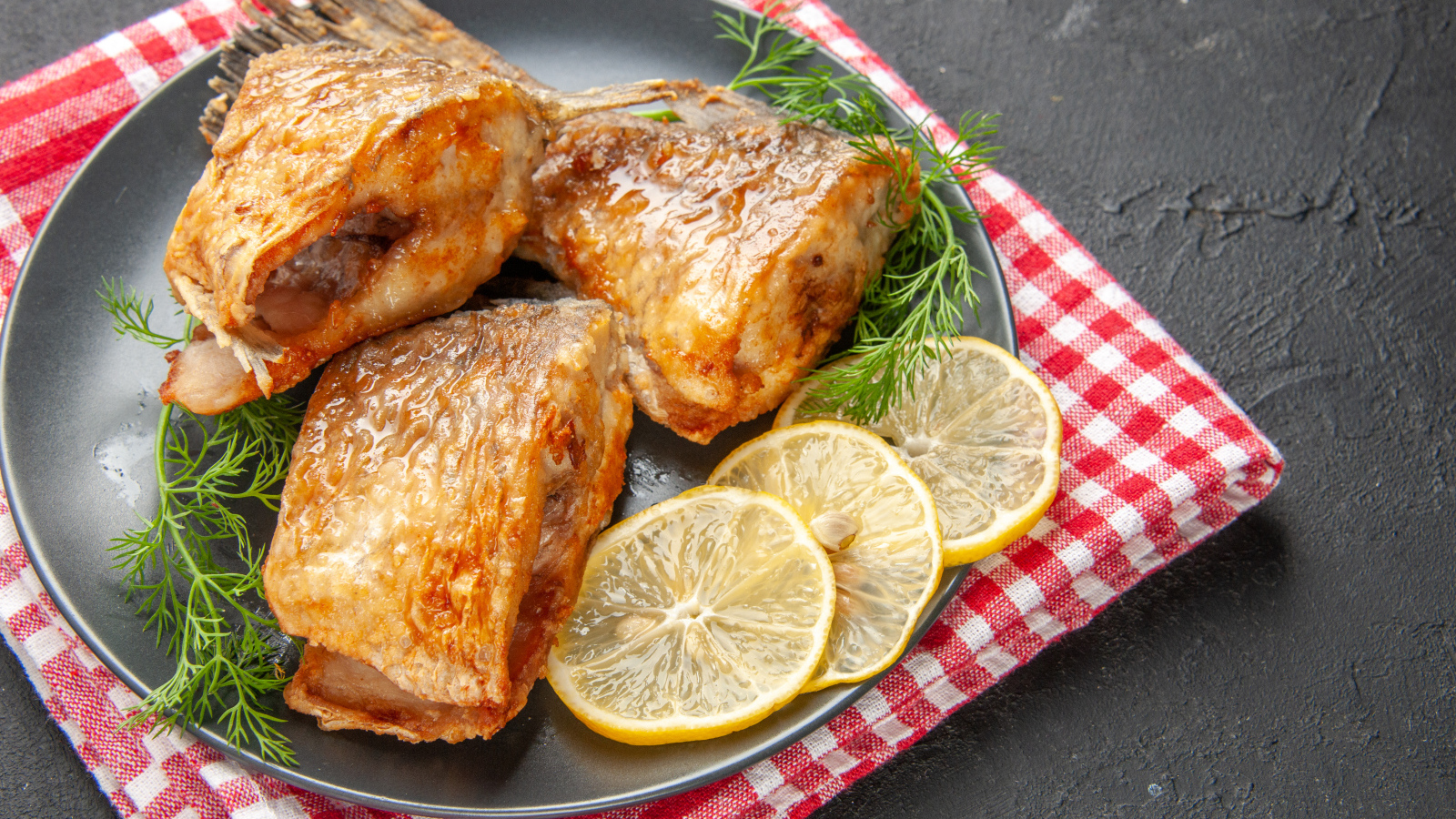 Куски жареной рыбы на тарелке с кусочками лимона и укропом