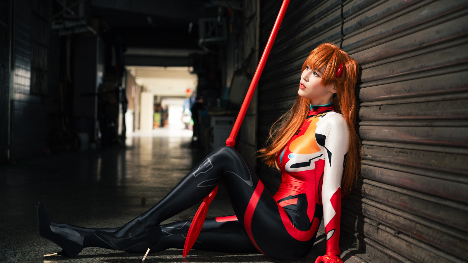 Девушка азиатка в костюме сидит у стены