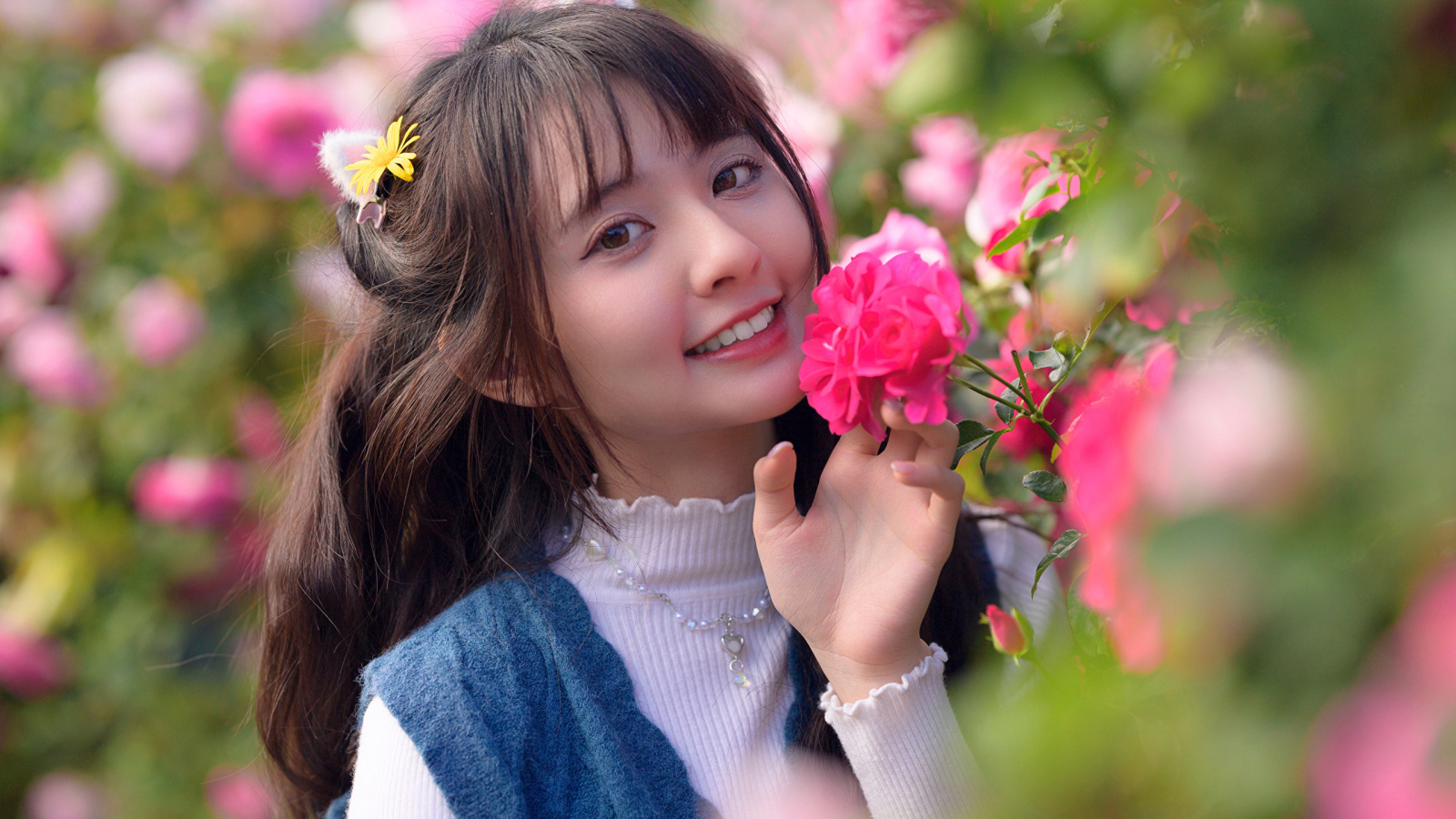 Красивая улыбающаяся азиатка с розовым цветком розы