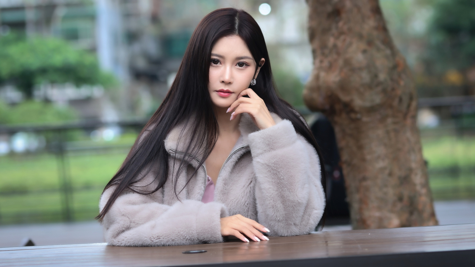 Кареглазая азиатка сидит в парке за столом