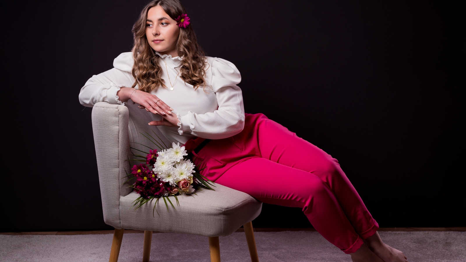 Милая девушка сидит на сером кресле с цветами