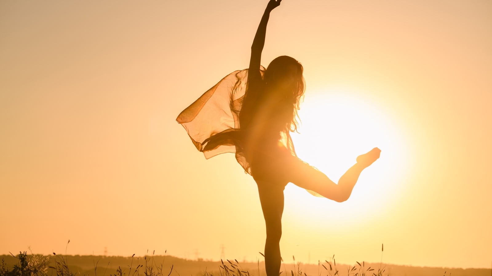 Девушка танцует в лучах солнца на закате
