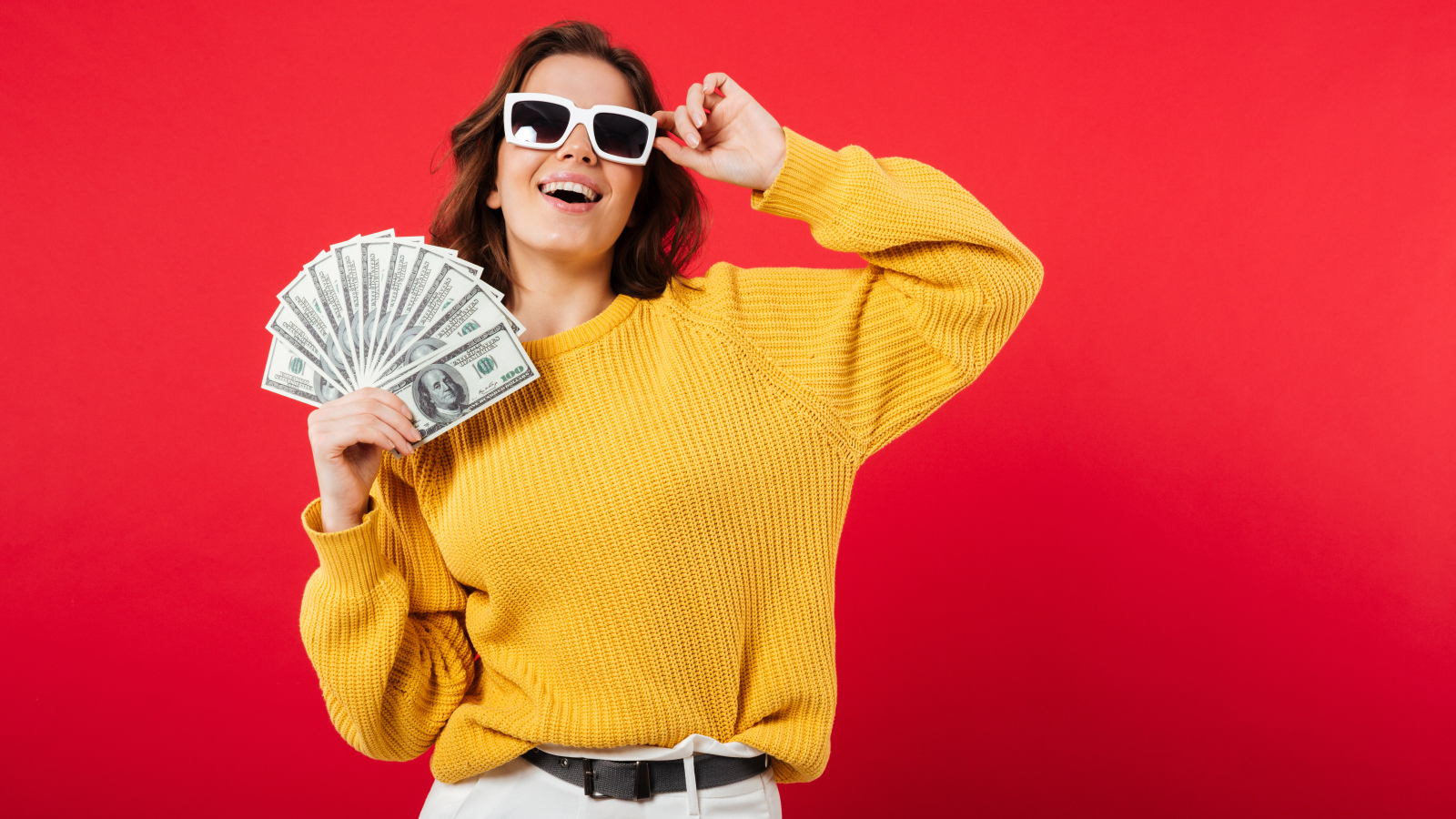 Девушка с веером из долларов на красном фоне