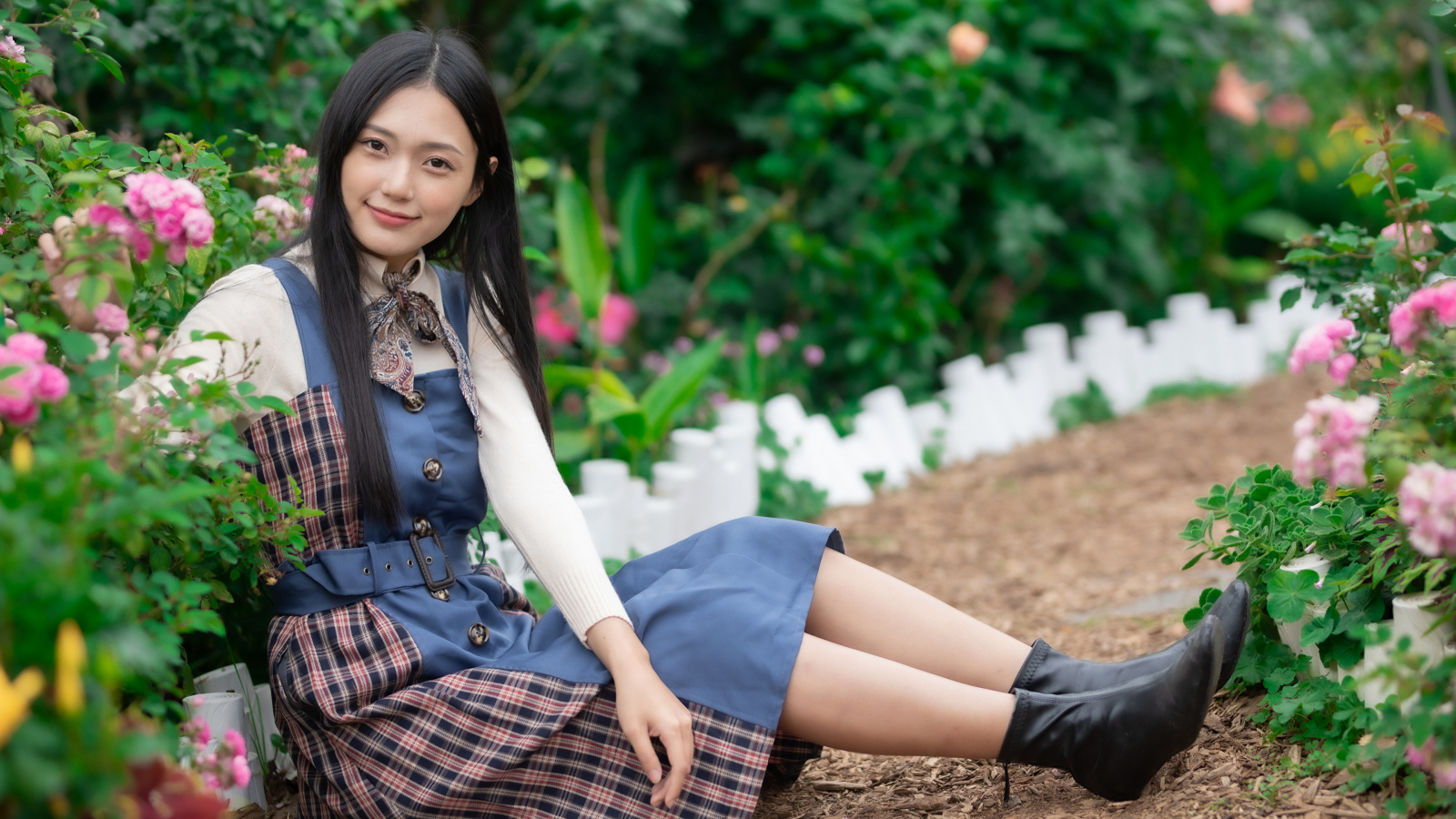 Настоящая молодая азиатка сидит на земле у клумбы