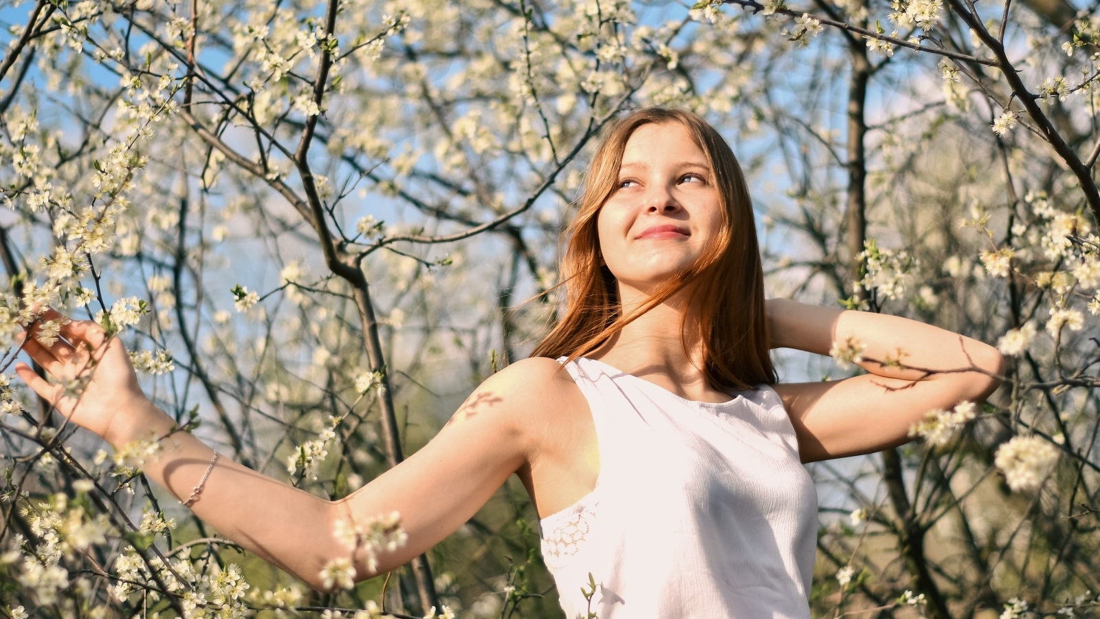 Молодая девушка у цветущего дерева весной