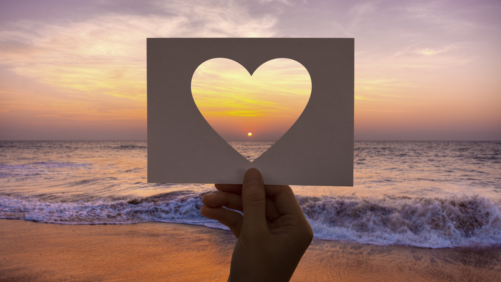 Бумажное сердце на фоне моря на закате солнца