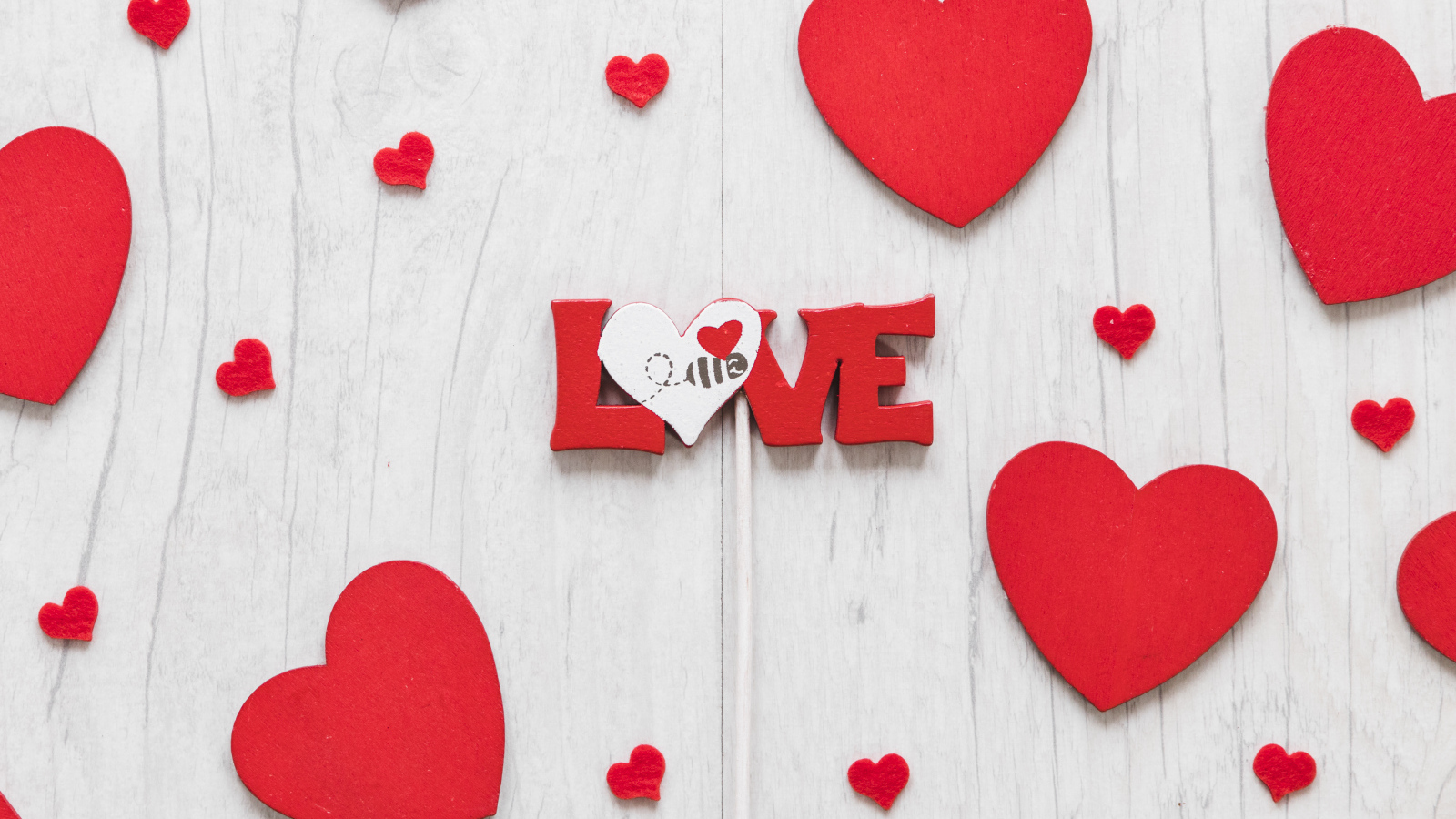 Надпись любовь с красным сердечками на деревянном фоне