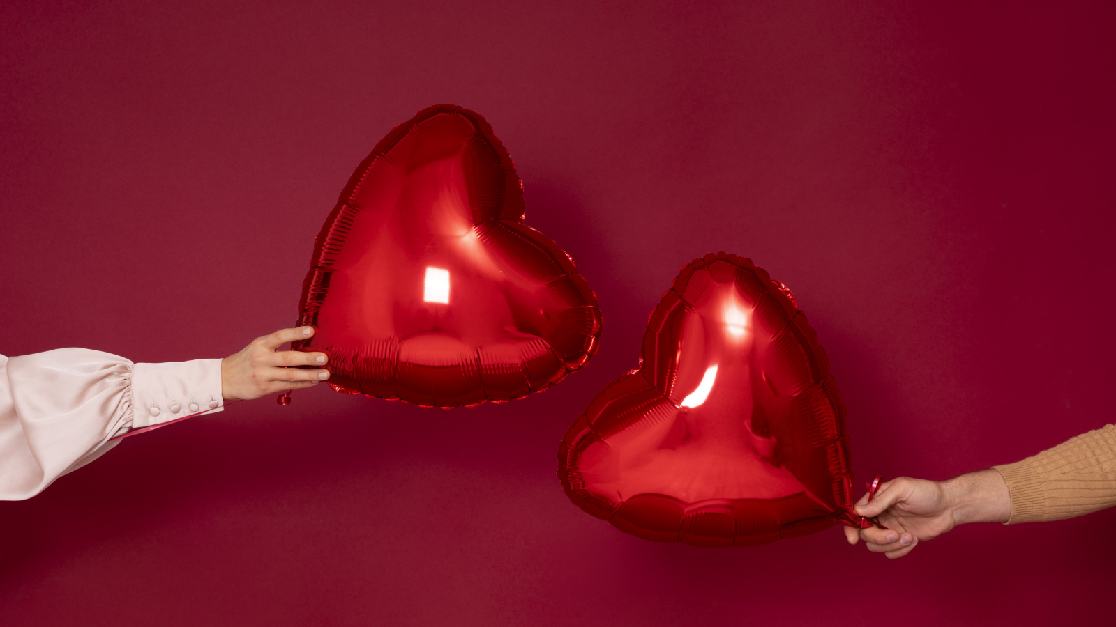 Два воздушных шара в форме сердца на красном фоне