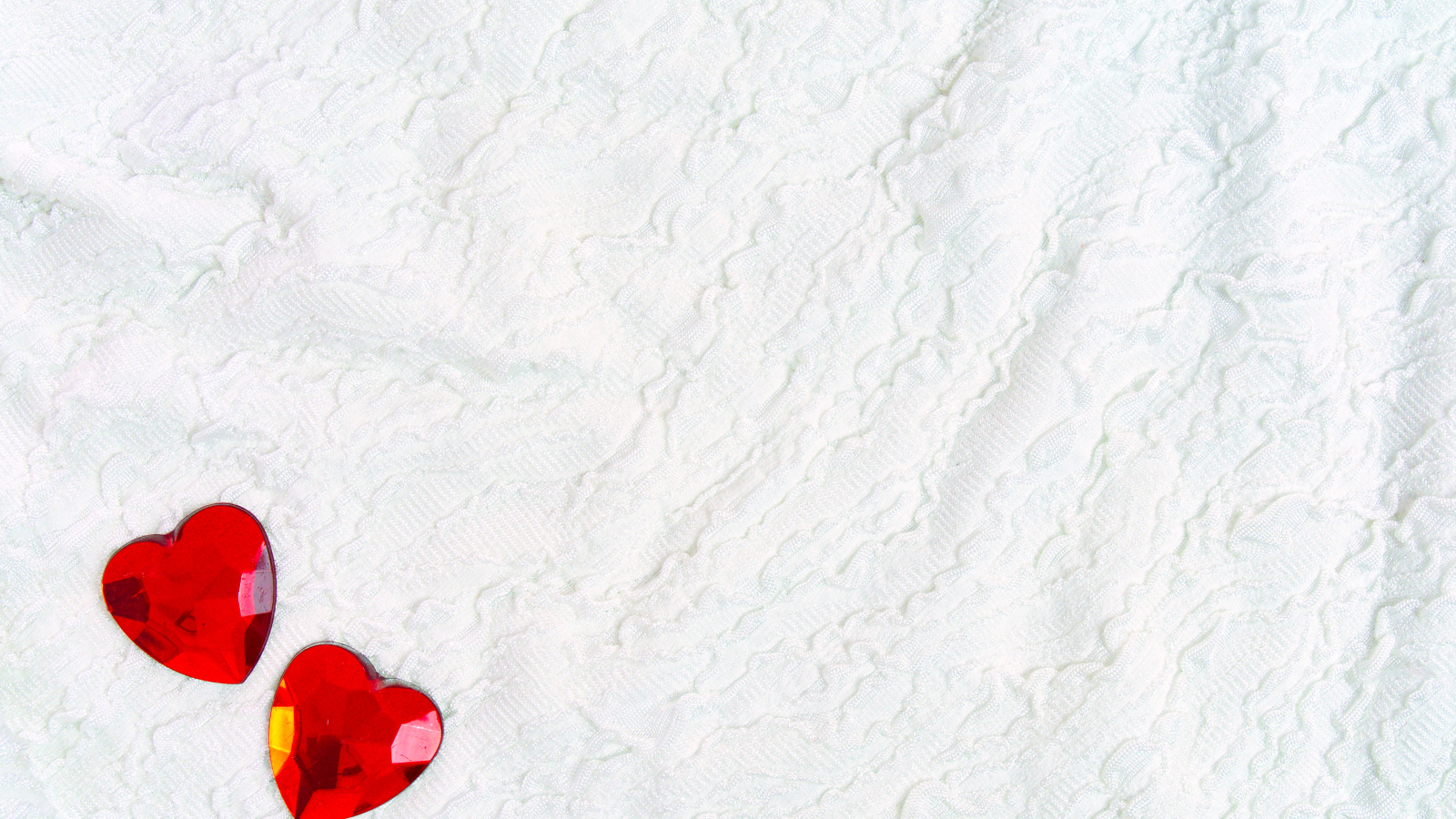 Два красных сердца из пластика на белой ткани