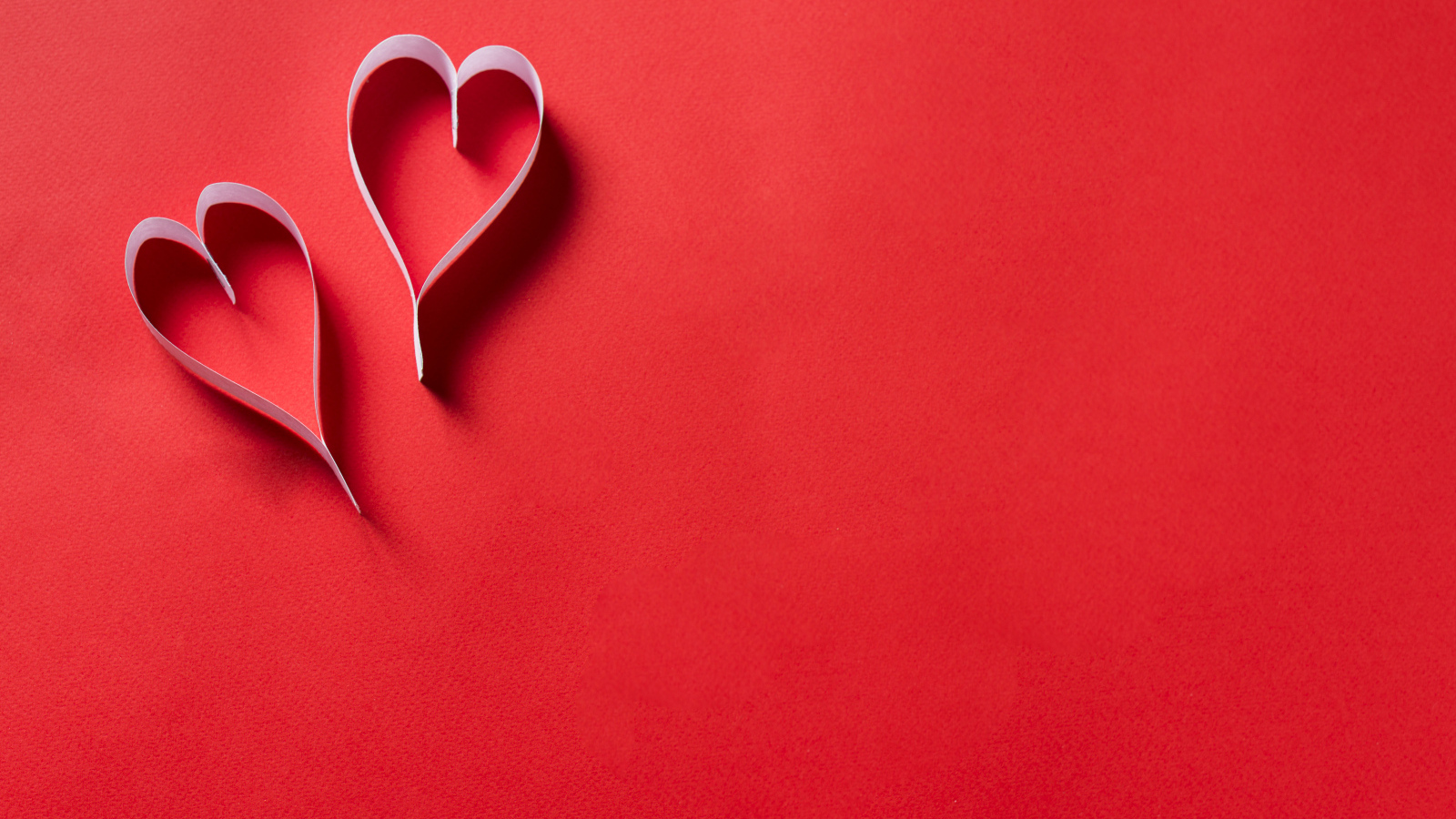 Два белых бумажных сердца на красном фоне