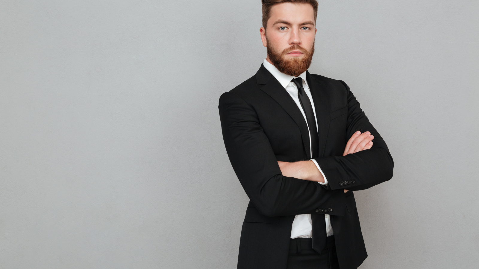 Деловой стильный мужчина в черном костюме на сером фоне