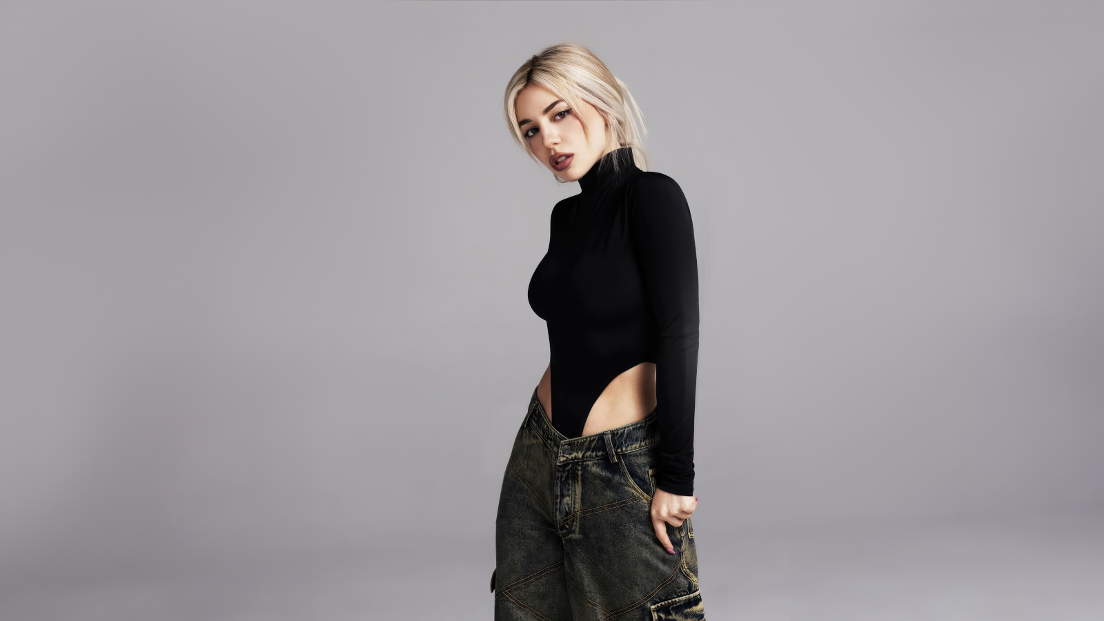 Милая блондинка певица  Эйва Макс на сером фоне