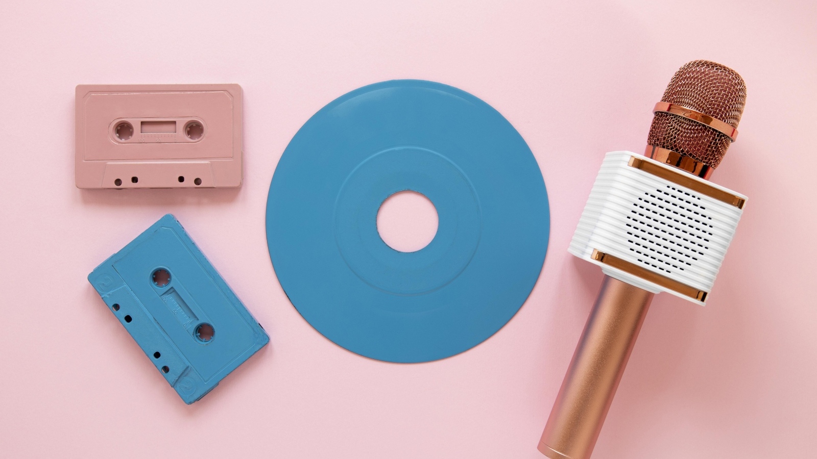 Две кассеты, микрофон и пластинка на розовом фоне