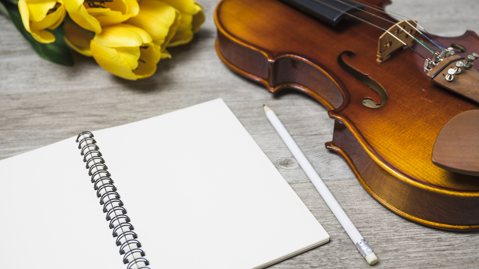 Скрипка, блокнот и желтые тюльпаны на столе
