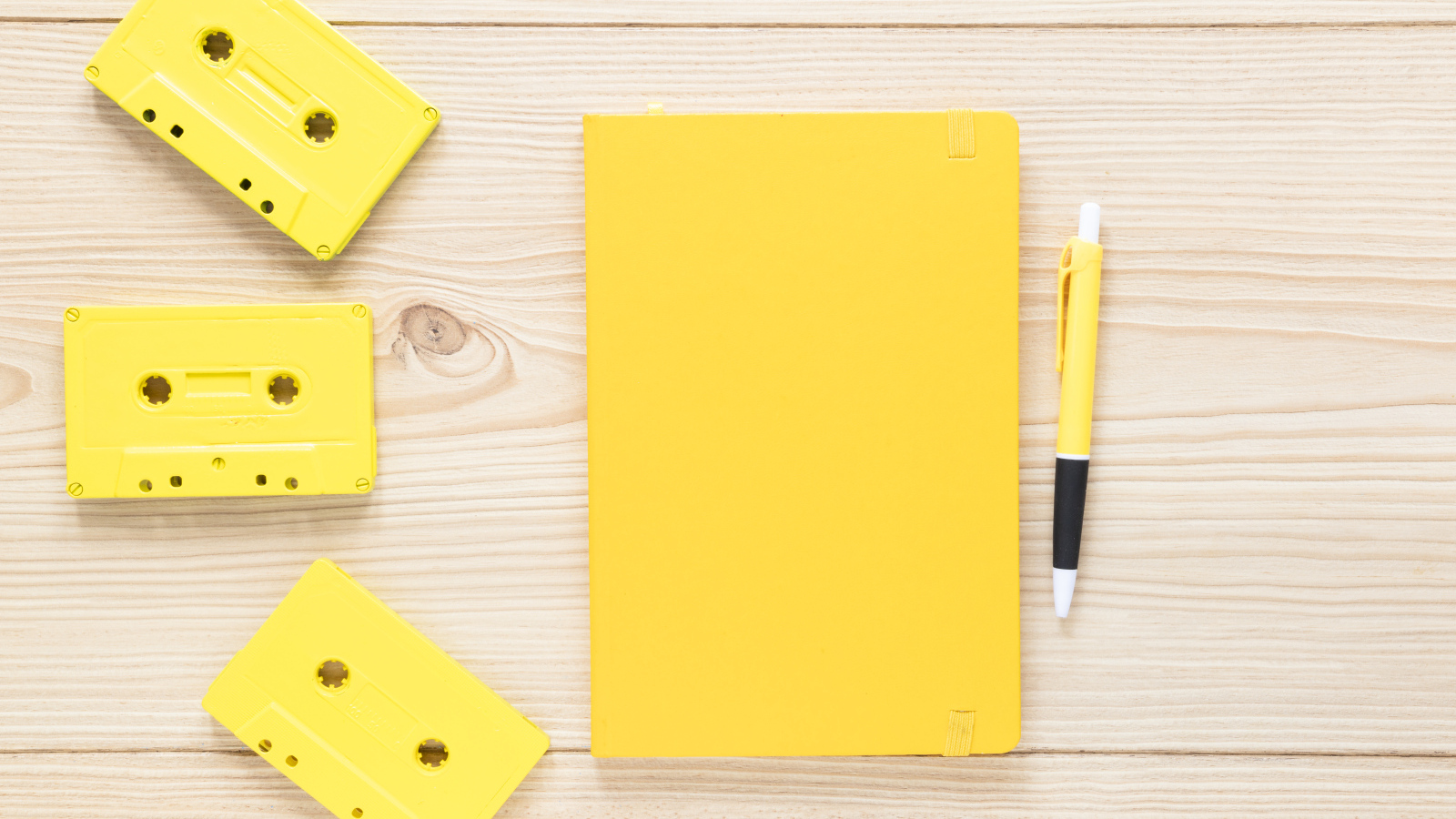 Желтый блокнот с ручкой и кассетами на столе