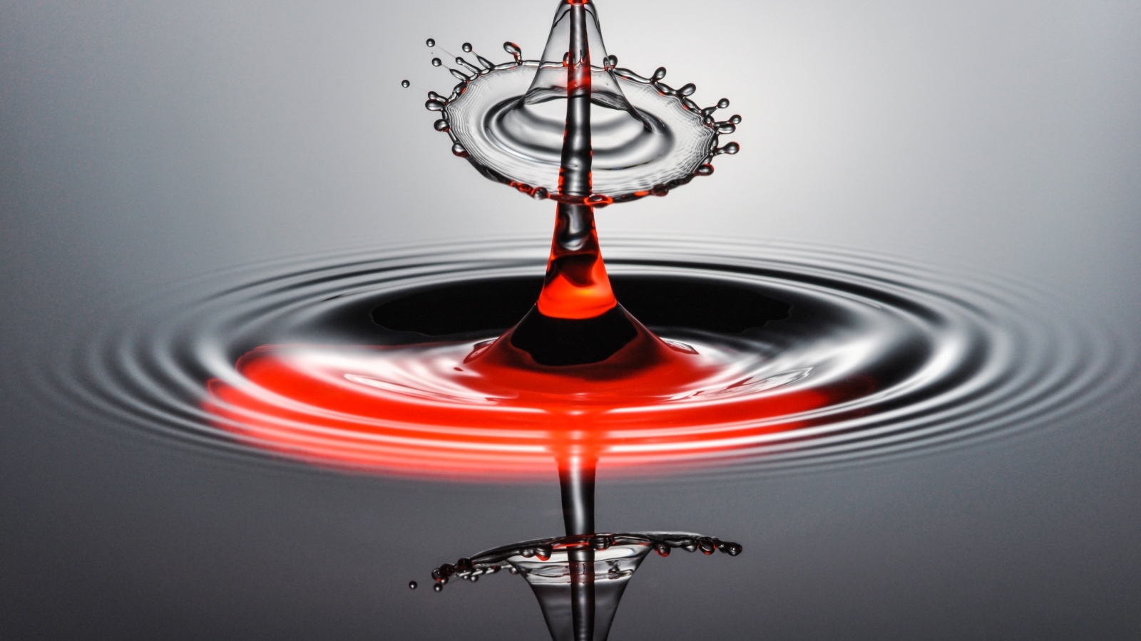 Брызги от капли воды на серой поверхности