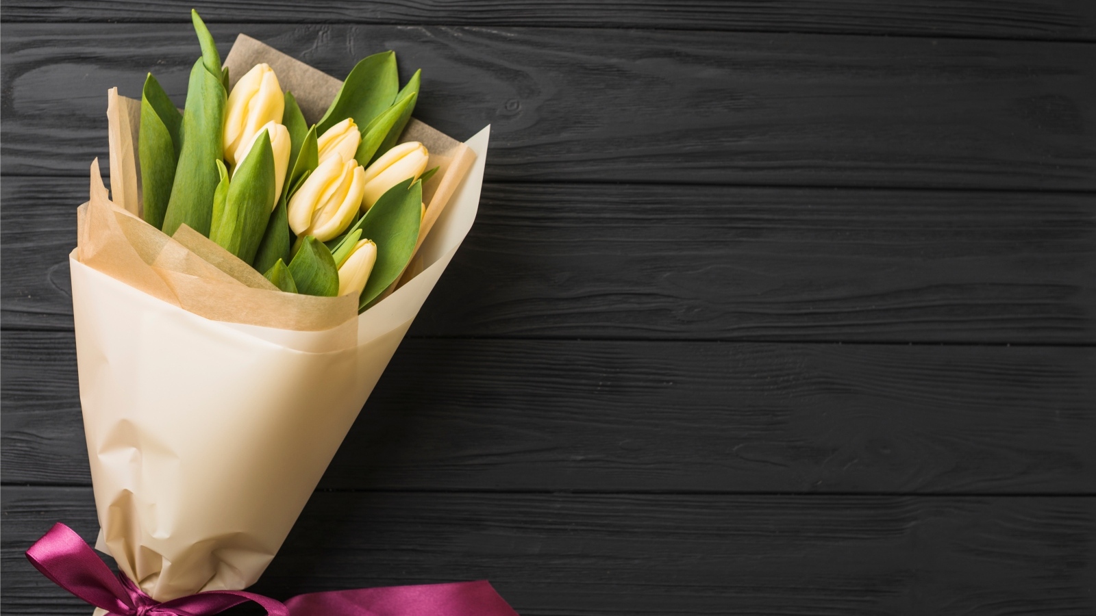 Букет желтых тюльпанов в бумажной упаковке с лентой