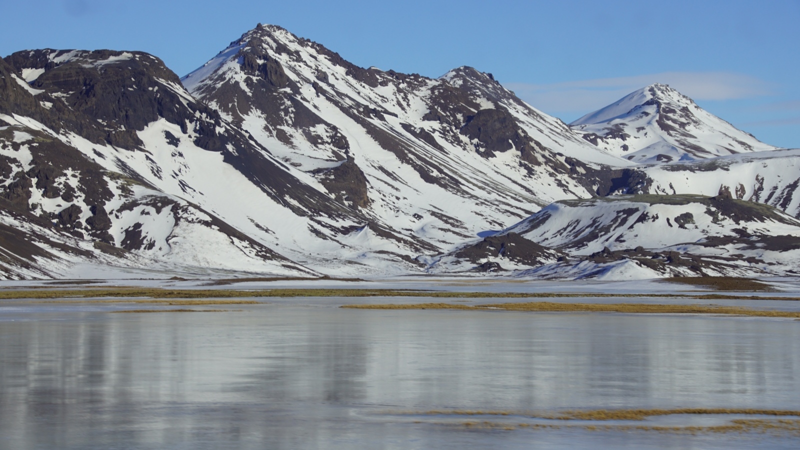 Горы в снегу под голубым небом у воды