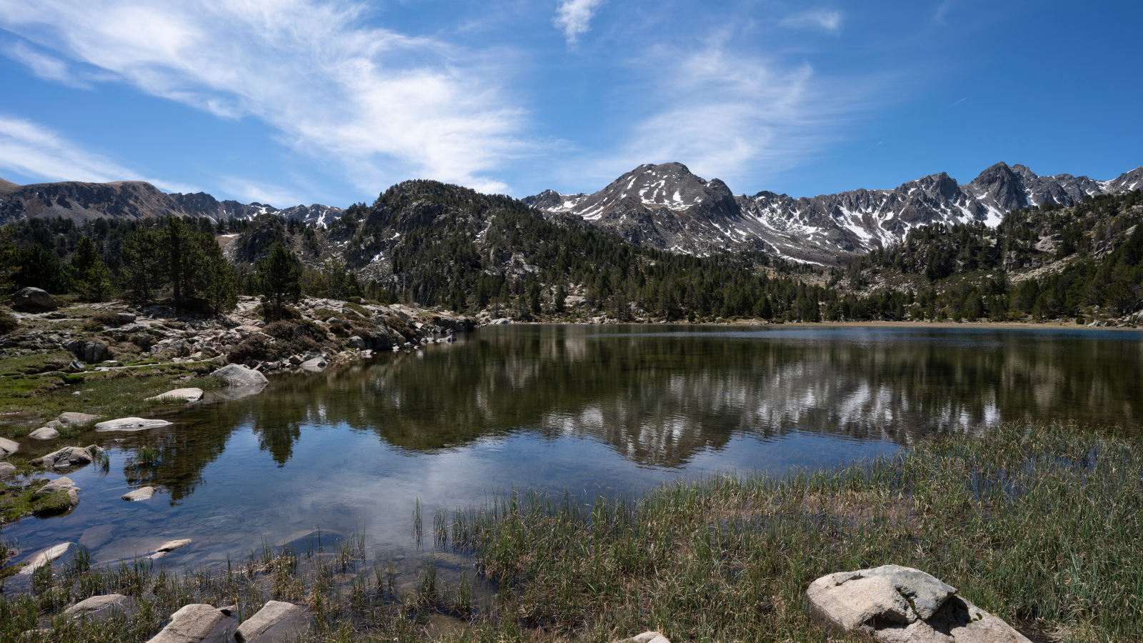 Горы отражаются в воде озера с большими камнями