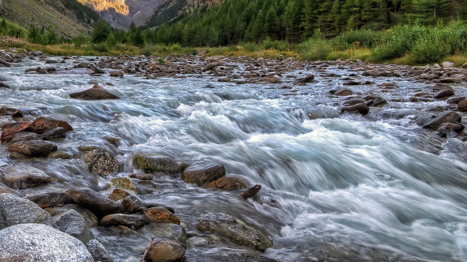 Быстрая холодная река стекает по камням в горах 