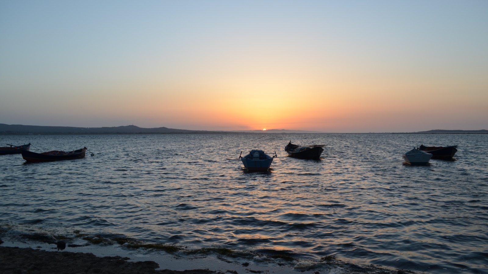 Лодки на морском побережье на закате