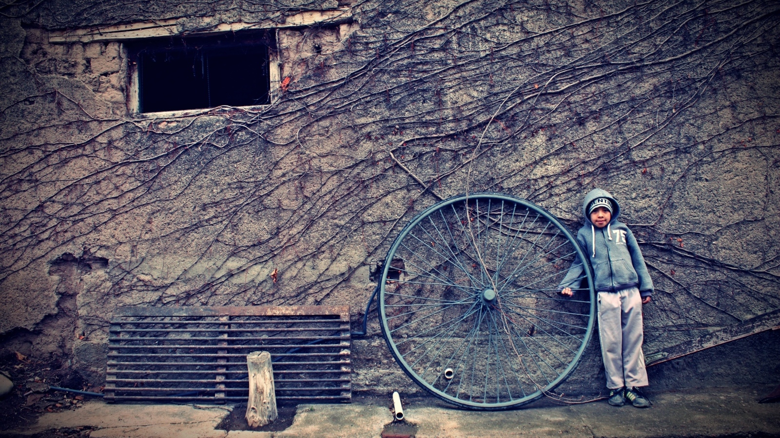 Мальчик с большим колесом стоит у стены