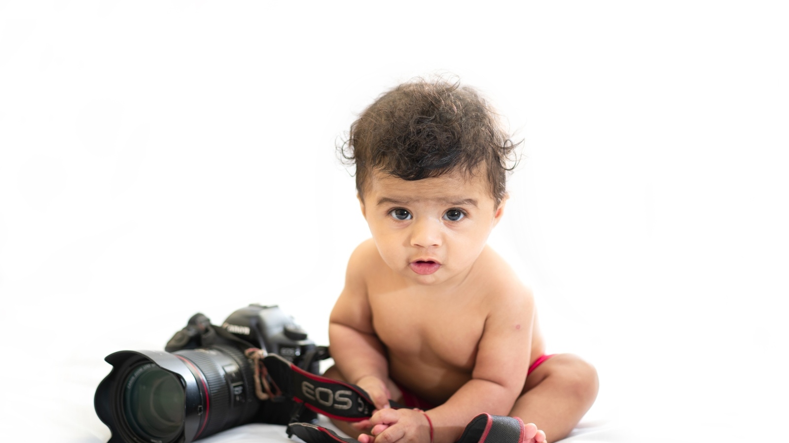 Милый ребенок с фотоаппаратом на белом фоне
