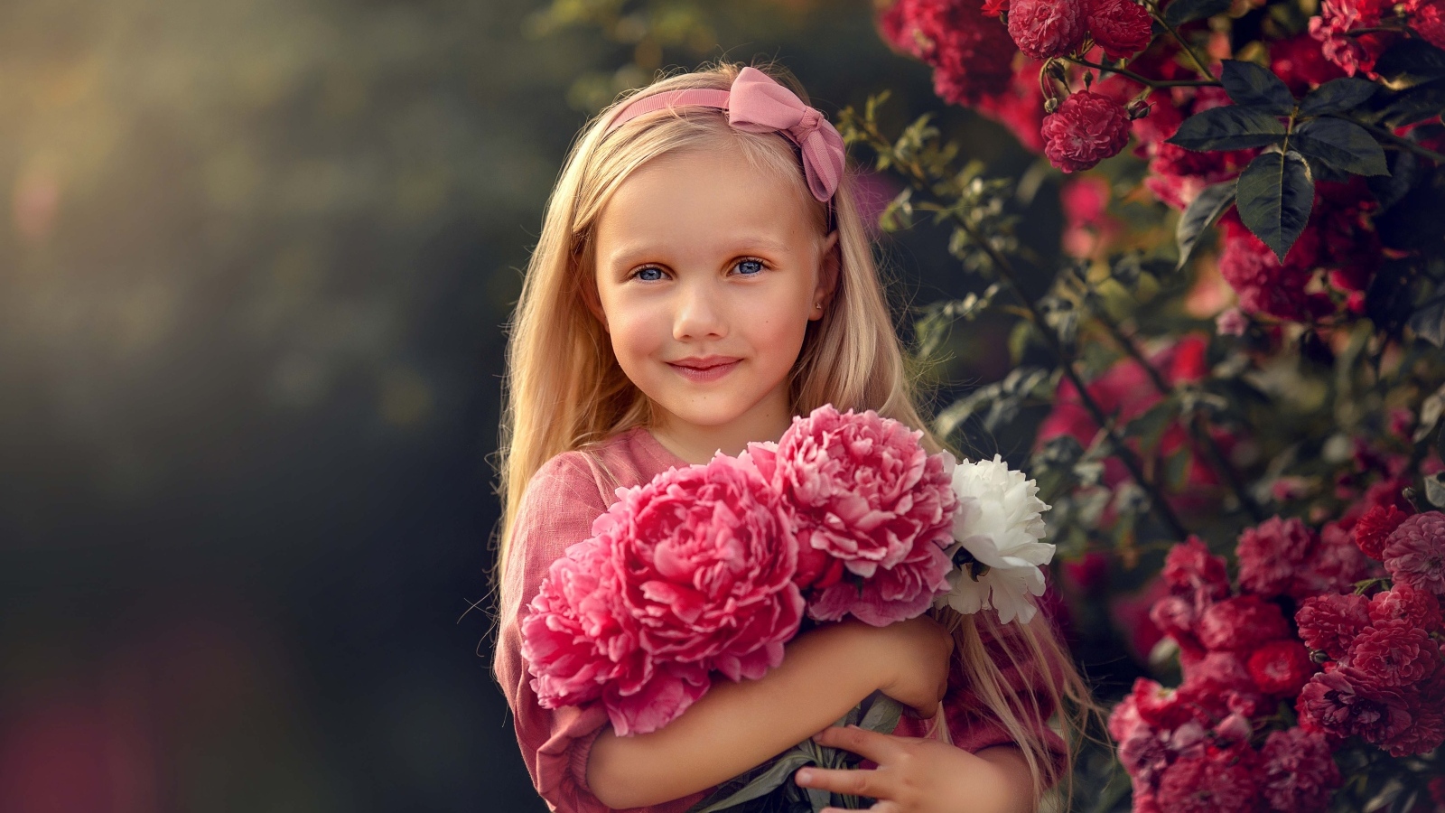 Милая маленькая девочка с букетом пионов