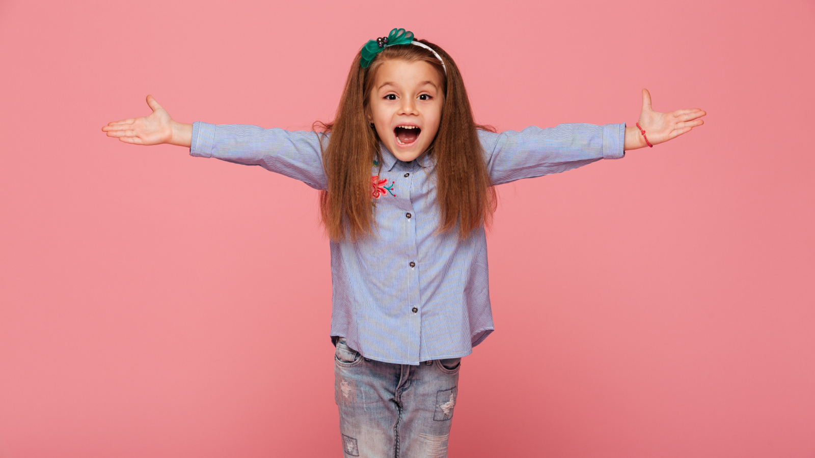 Счастливая маленькая девочка на розовом фоне