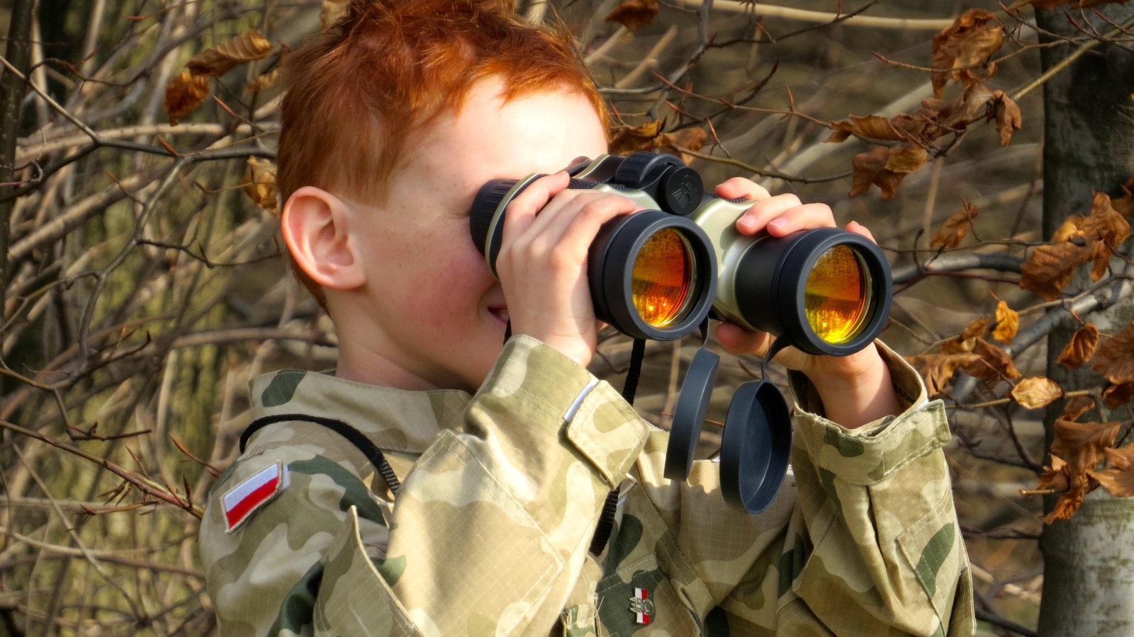 Маленький мальчик в военной форме с биноклем в руках