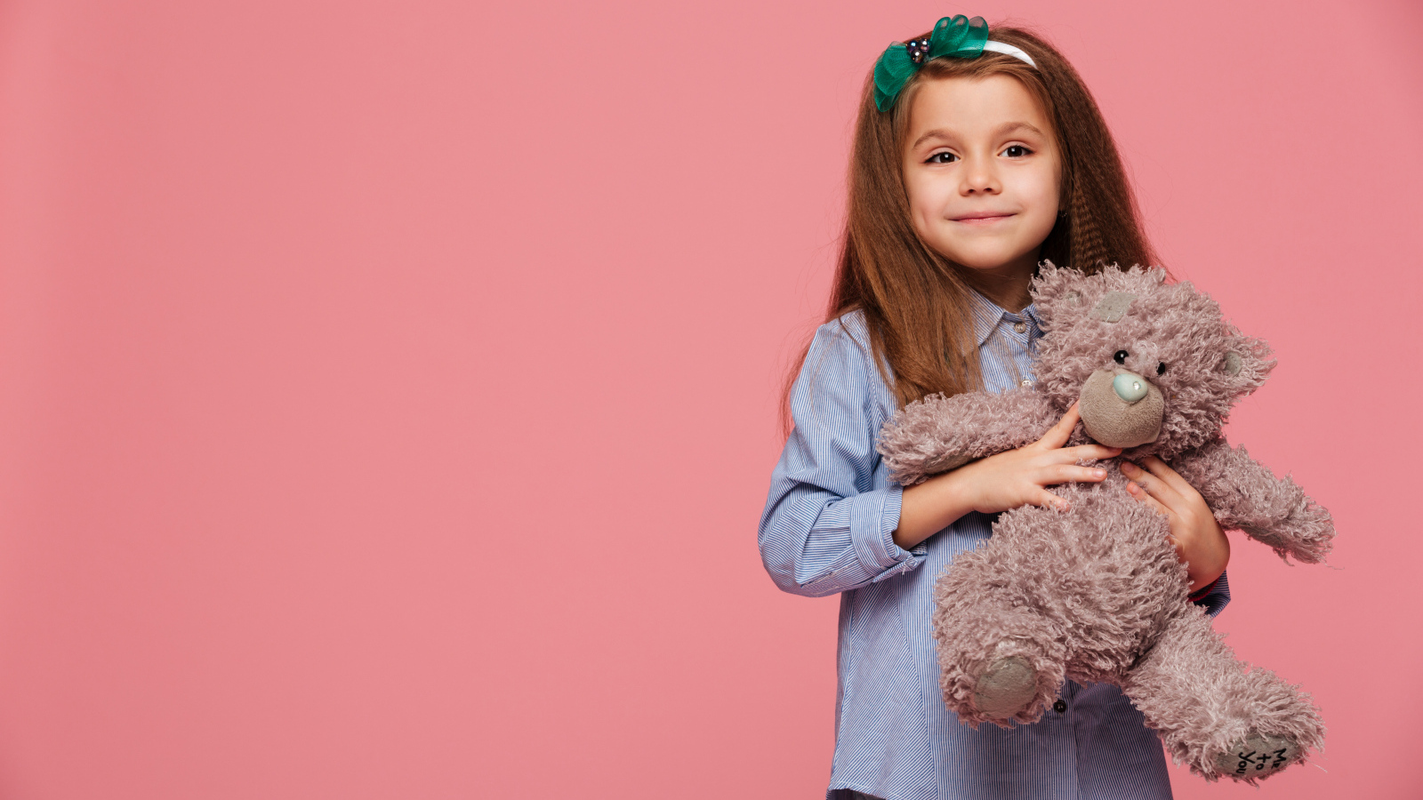 Маленькая девочка с игрушкой на розовом фоне