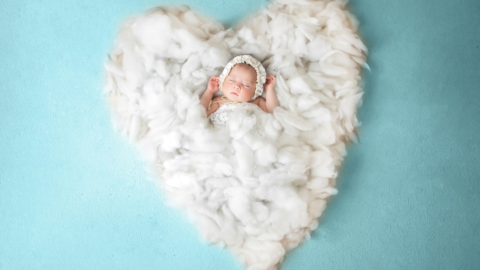 Новорожденный ребенок спит на белом мягком сердце на голубом фоне