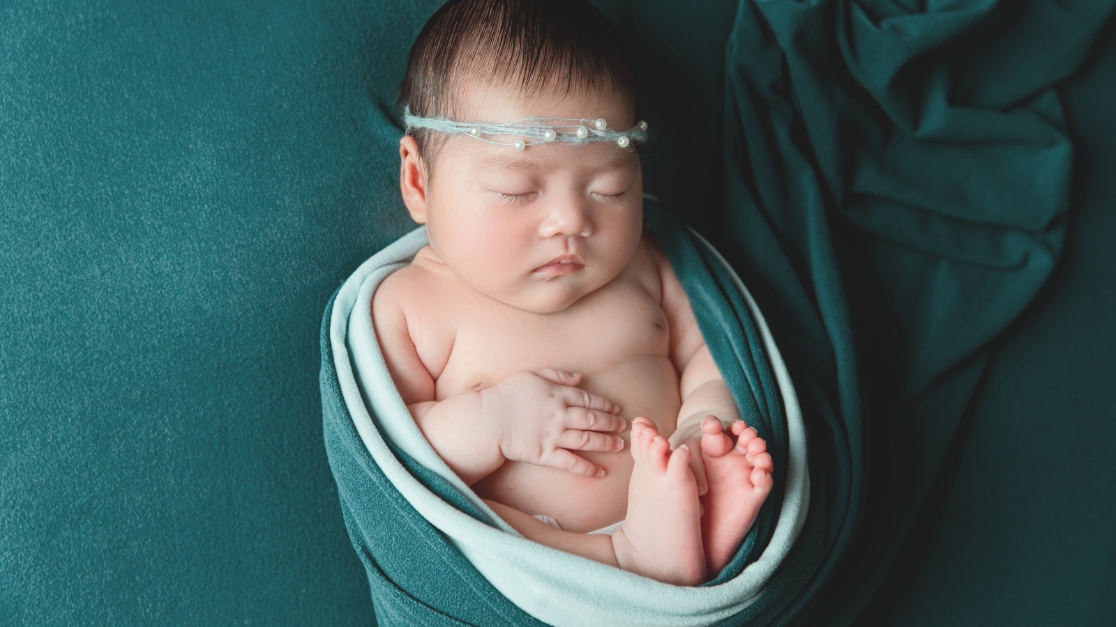 Фотография спящей новорожденной девочки на зеленом фоне