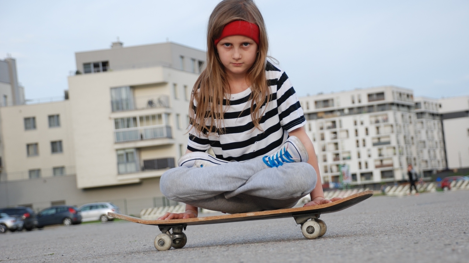 Серьезная девочка сидит на  скейтборде