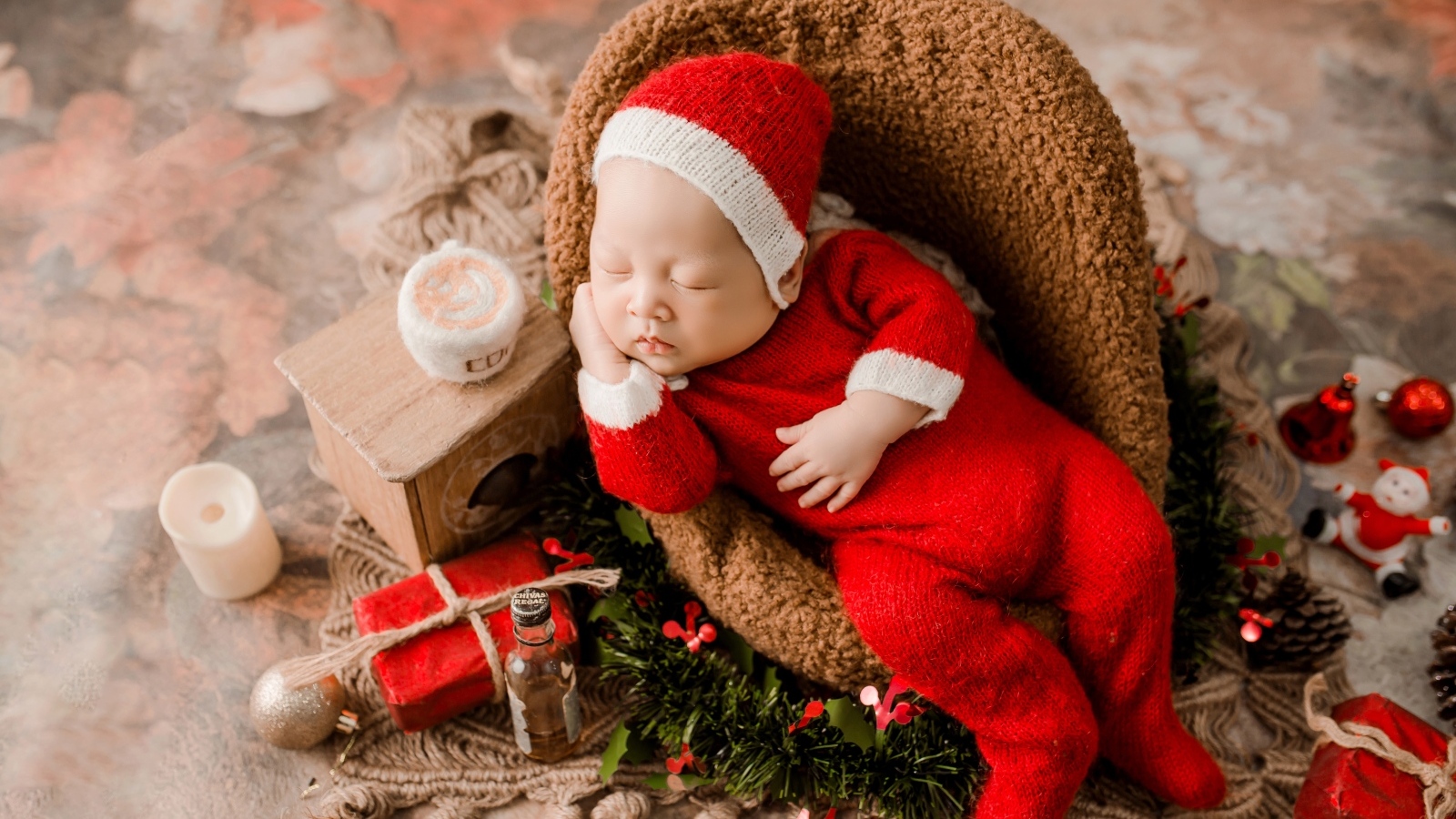 Спящий новорожденный ребенок в красном новогоднем костюме