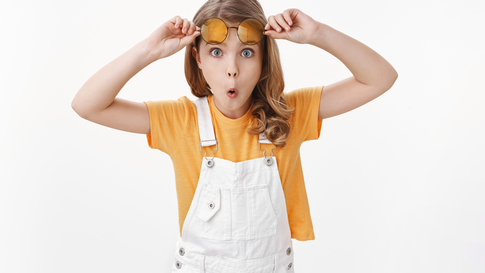 Удивленная девочка в очках на белом фоне