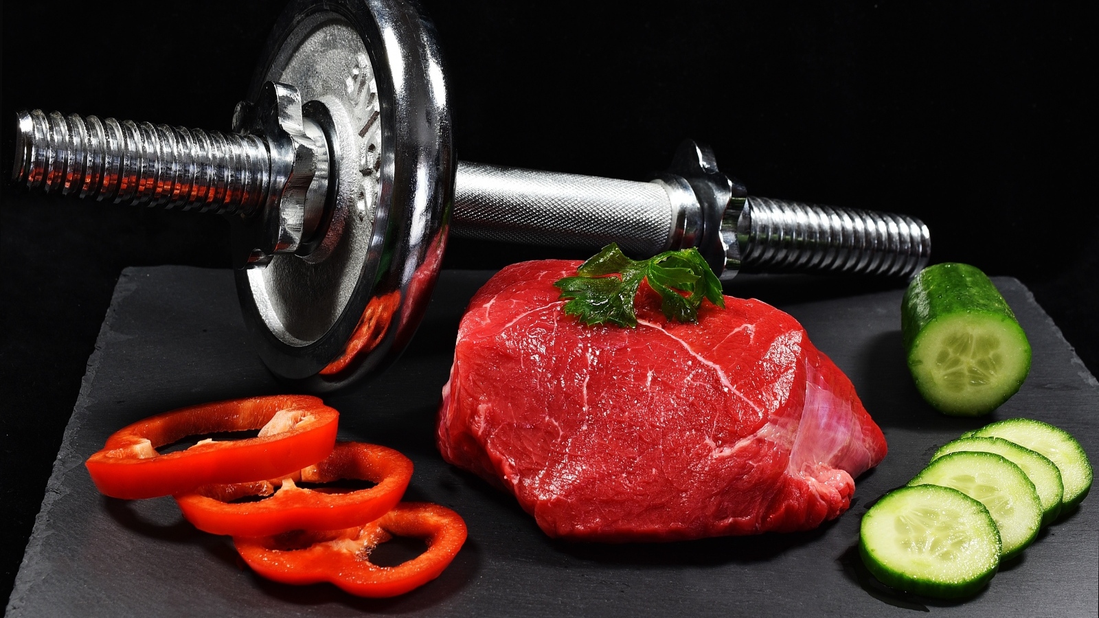 Гантеля и полезная еда для спортсмена на черном фоне