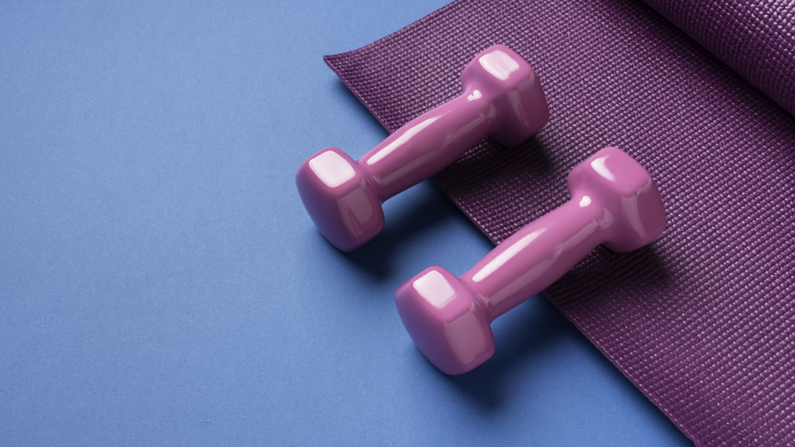 Розовые гантели и коврик на голубом фоне