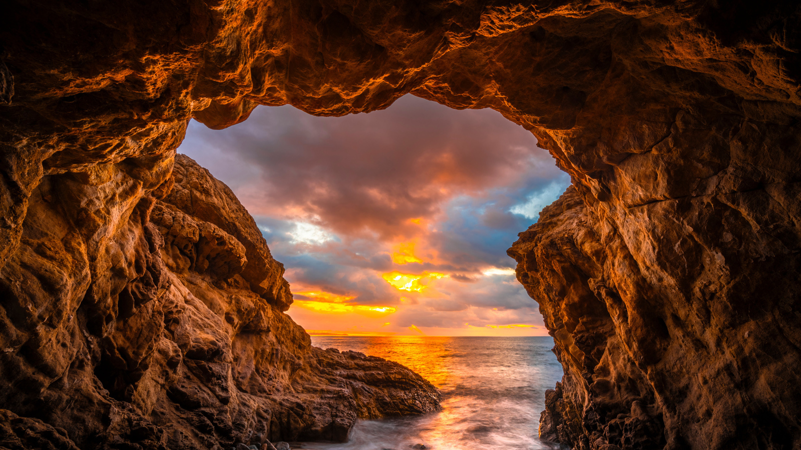 Арка в горе на закате солнца на пляже Малибу, США