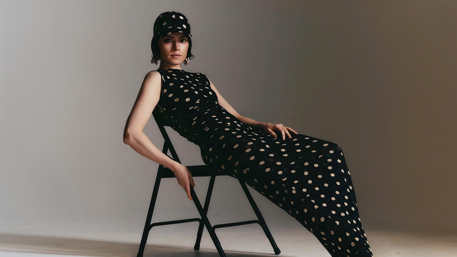 Актриса Дейзи Ридли в черном платье сидит на стуле