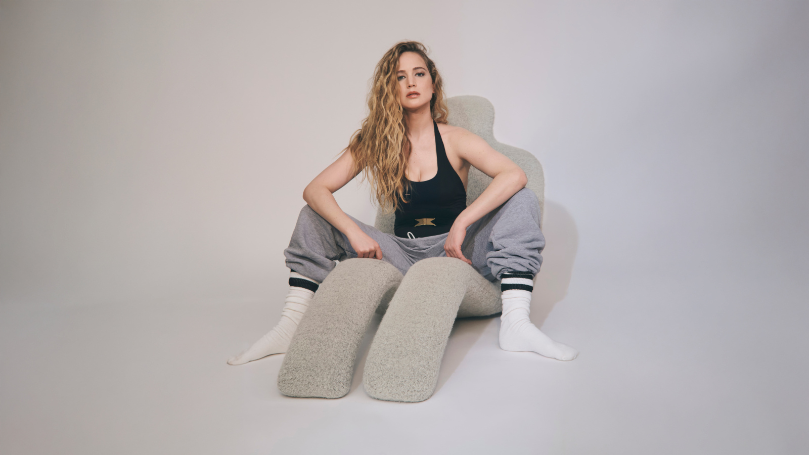 Красивая актриса Дженнифер Лоуренс  сидит на сером кресле