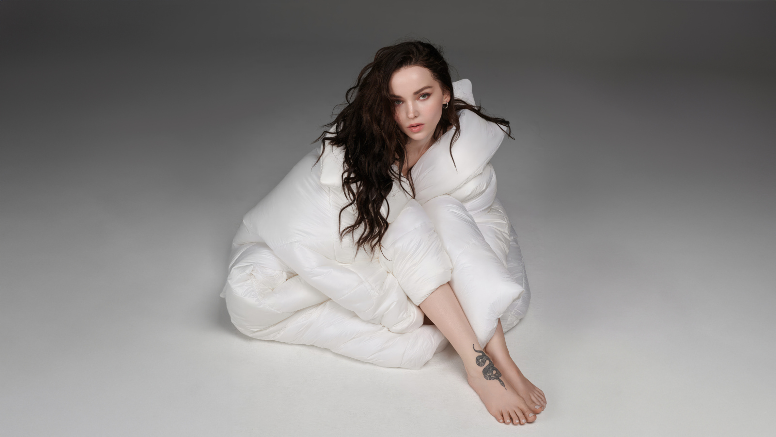 Красивая брюнетка Дав Кэмерон в белом костюме на сером фоне